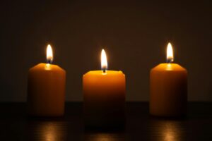 Three glowing candles in darkness, symbolizing peace and meditation. Perfect for calming and spiritual themes.
